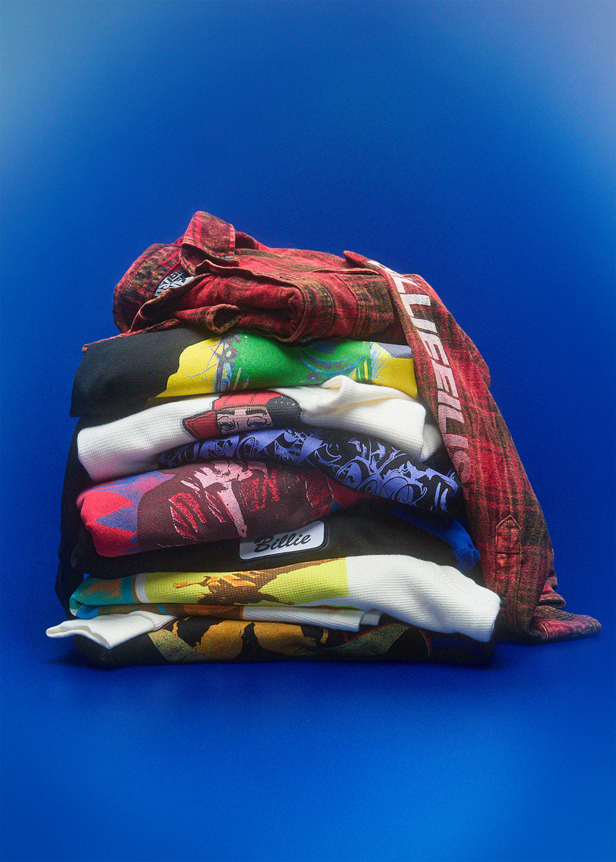 Stack of folded colorful shirts on a blue background Billie Eilish Merchandise apparel
